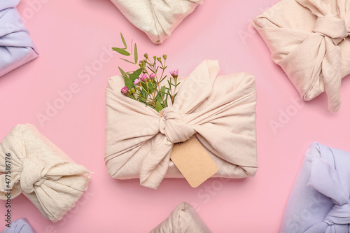 Many gift boxes wrapped in fabric on pink background
