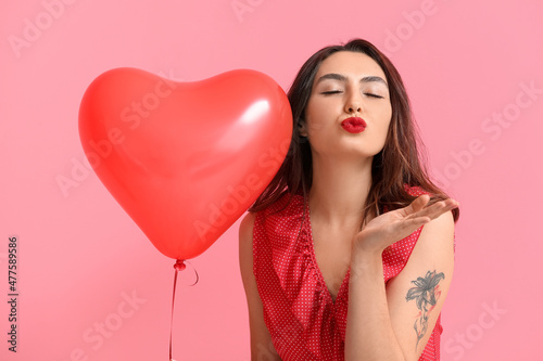 Beautiful young woman with balloon blowing kiss on color background. Valentine's Day celebration © Pixel-Shot