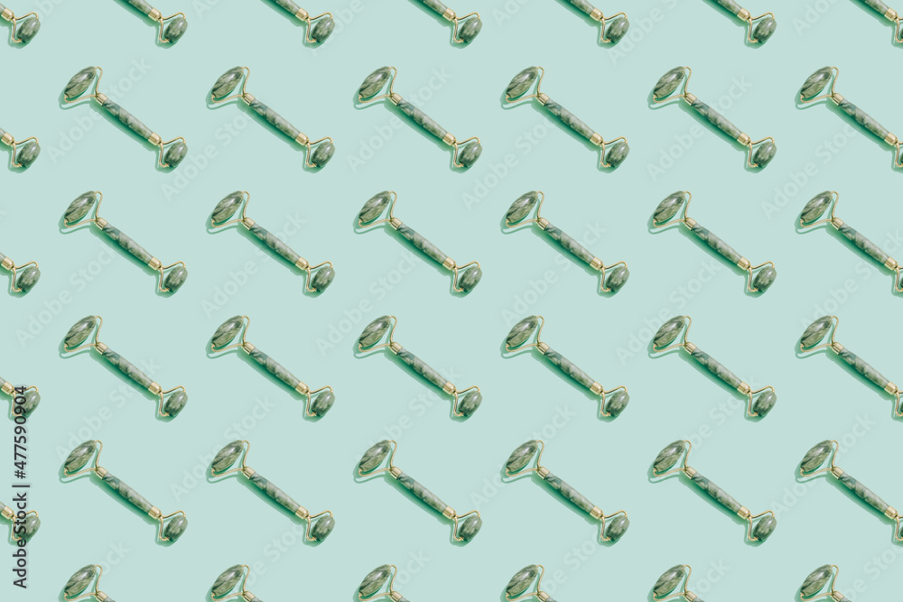Pattern made with jade gua sha facial roller on pastel green background. Facial massage kit for lifting massage therapy made from natural stones, personal skin care anti-aging tools.