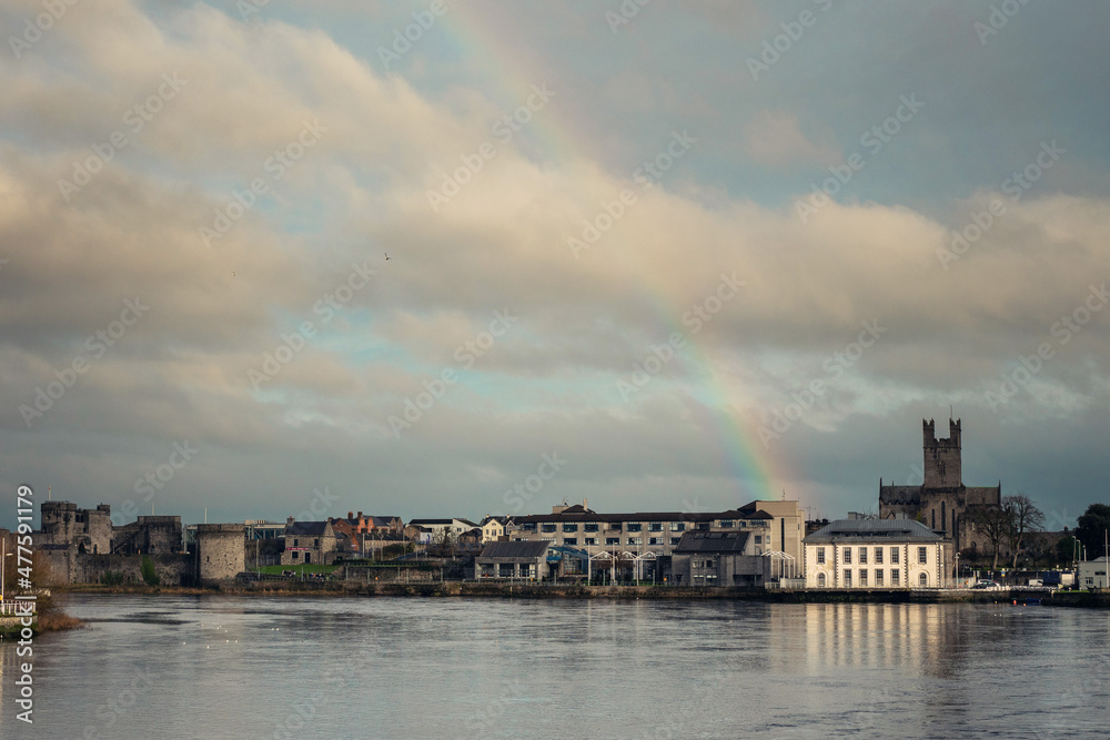 Rainbow in the sky over Limerick City District Court building and St Mary's Cathedral. Ireland. River Shannon. Popular town landmark and tourist spot. Cloudy sky. Irish luck and stunning nature event.