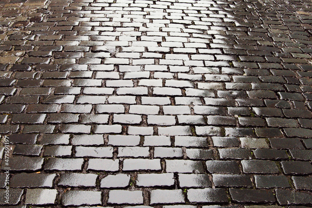 Wet cobble road surface after a rain. Old way pavement surface build to last for centuries.