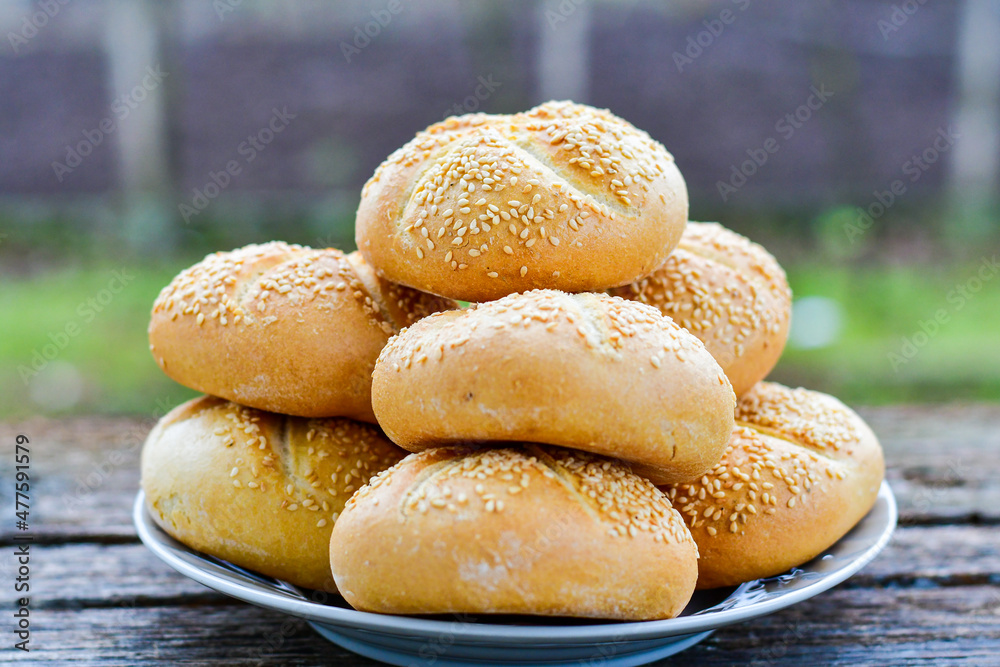 Tasty fresh crisp bakery product. Baked bund bread with sesame seeds on wooden rustic background. Outdoor in a village Tasty fresh crisp bakery product. Baked bund bread with sesame seeds on wooden rustic background. Outdoor in a village