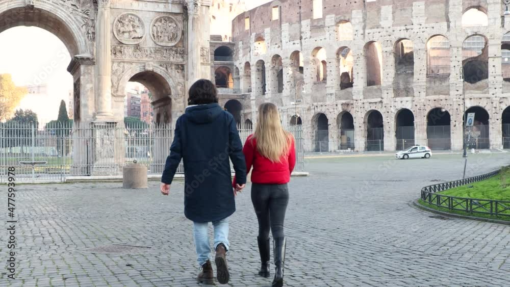 Young couple traveling to Rome. The young couple is walking in front of the Arch of Titus and admiring the beauty of Roma.
