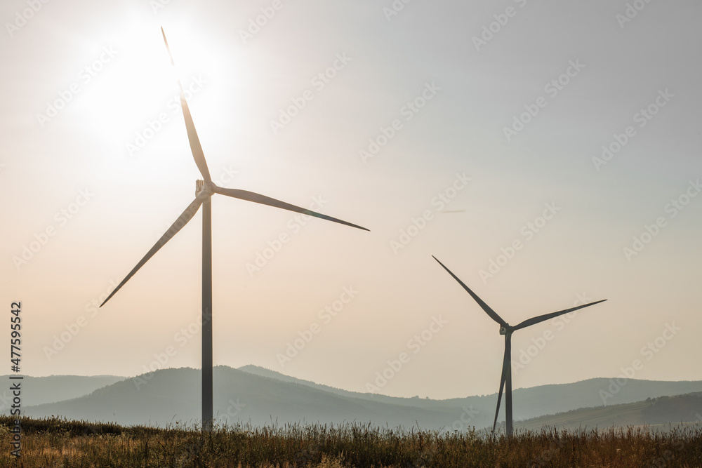 Alternative energy wind turbines standing and working on green farm. Summer sunset on background. Countryside landscape. Alternative energy wind turbines standing and working on green farm. Summer sunset on background. Countryside landscape.