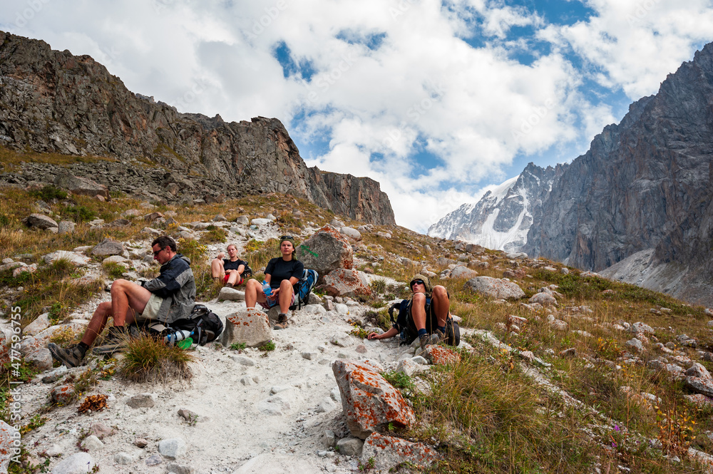 Group of trekkers backpackers ascending from Ala-Archa to Ak-Sai Racek Hut and Glacier. Ala Archa Alpine National Park Landscape near Bishkek, Tian Shan Mountain Range, Kyrgyzstan, Central Asia.