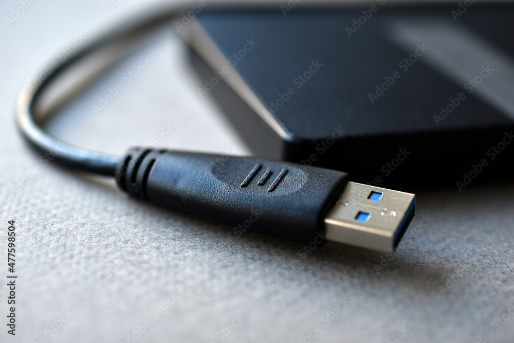 External hard drive with usb cable on a gray background External hard drive with usb cable on a gray background
