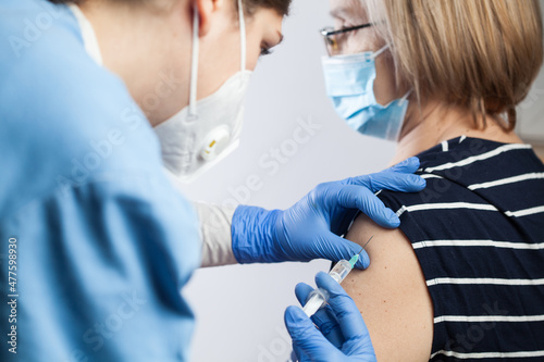 Female medical worker injecting Coronavirus booster dose to elderly patient photo