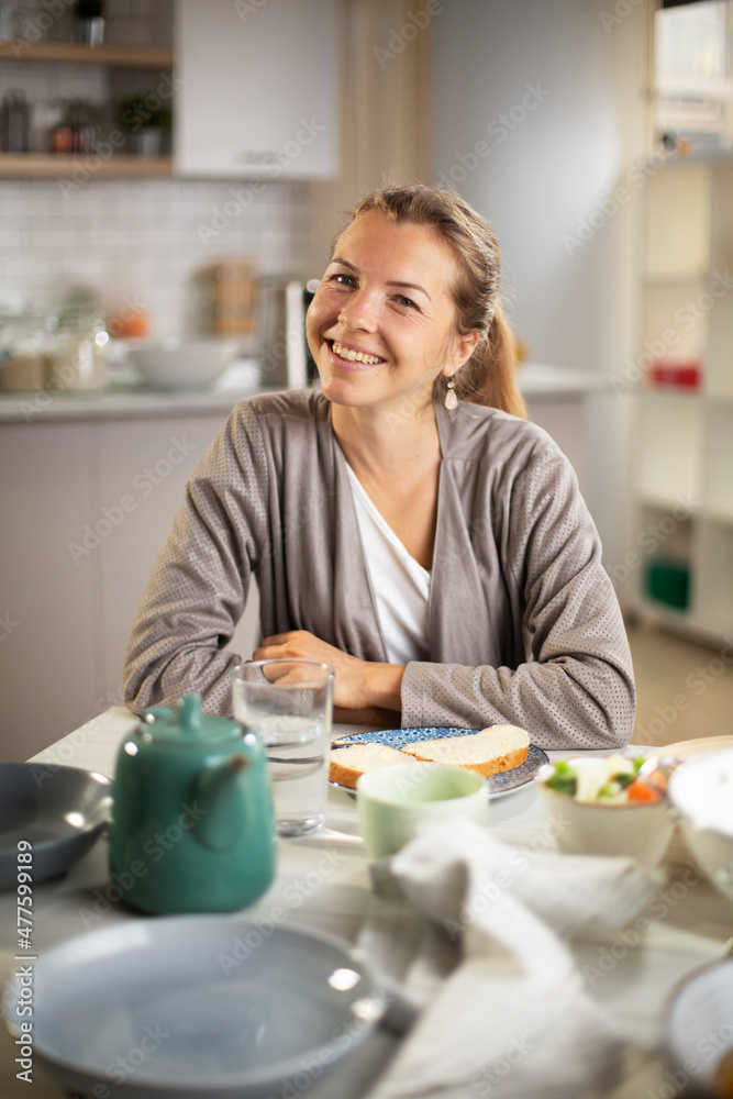 Beautiful woman enjoying in breakfast. Happy young woman eating sandwich at home..