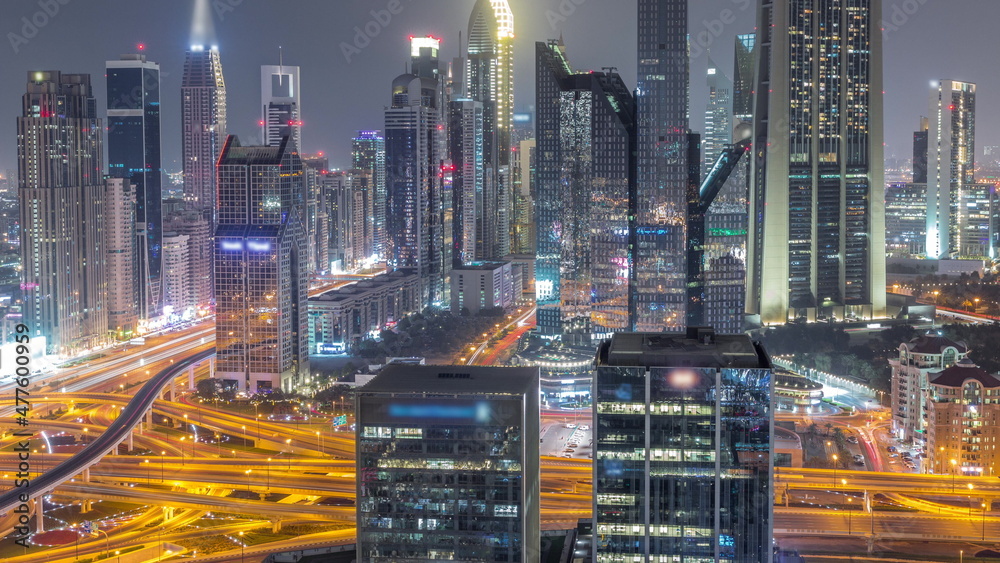 Panorama of Dubai Financial Center district with tall skyscrapers illuminated all night timelapse.