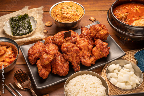 Traditional Korean food, Korean Fried chicken with spicy sauce with rice, seaweed and Kimchi pickle on wooden table.