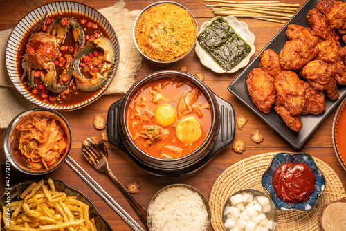 Traditional Korean food, kimchi soup, Korean Fried chicken with spicy sauce  with rice, seaweed,fresh raw crabs marinated,spicy Rice Cake and Kimchi pickle on wooden table.