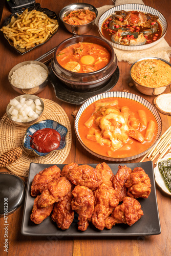 Traditional Korean food, Korean Fried chicken with spicy sauce  with rice, seaweed,fresh raw crabs marinated,spicy Rice Cake and Kimchi pickle on wooden table.