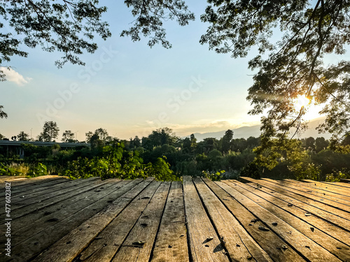 Wooden table and view of mountain with sun light, tree and bright sky.