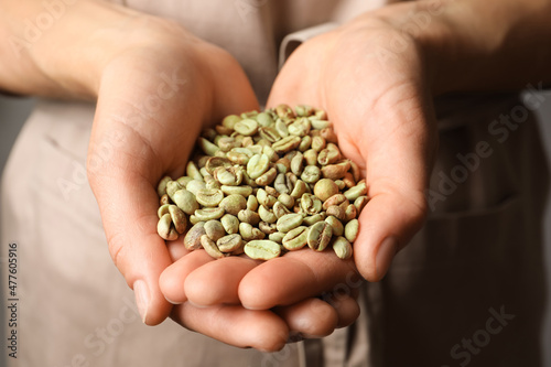 Woman holding pile of green coffee beans, closeup © New Africa