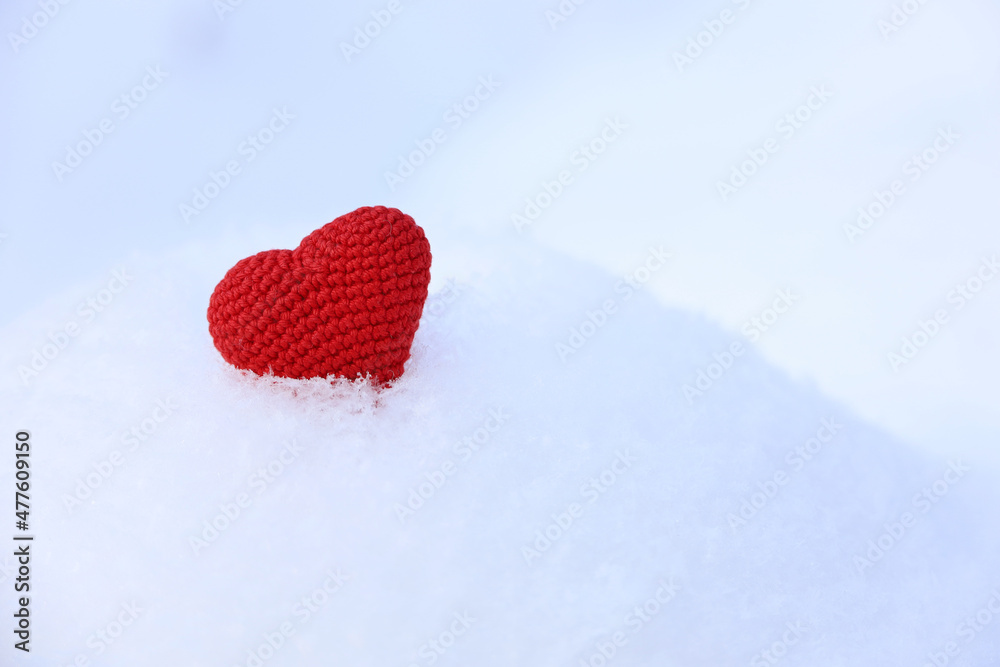 Red knitted love heart in the snow. Valentine's day card, background for Christmas or New Year celebration