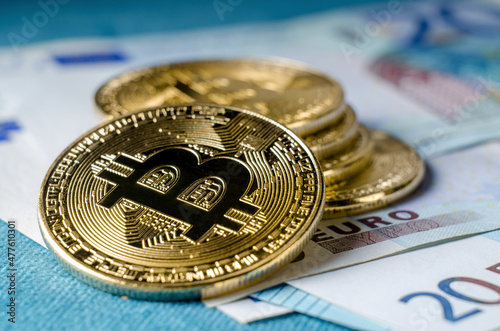 Physical Gold Bitcoin Coin against euro bills.