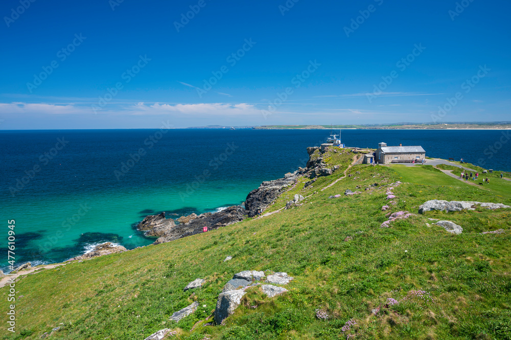 View of the coastal path, around the headland in St. Ives, Cornwall, England.  It is a summer's day and the sea is a clear blue and aqua colour. 