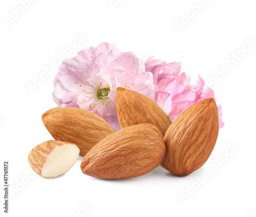 Tasty almonds and pink flowers on white background