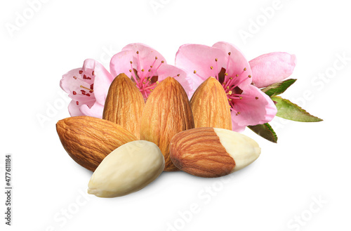 Tasty almonds, pink flowers and green leaves on white background
