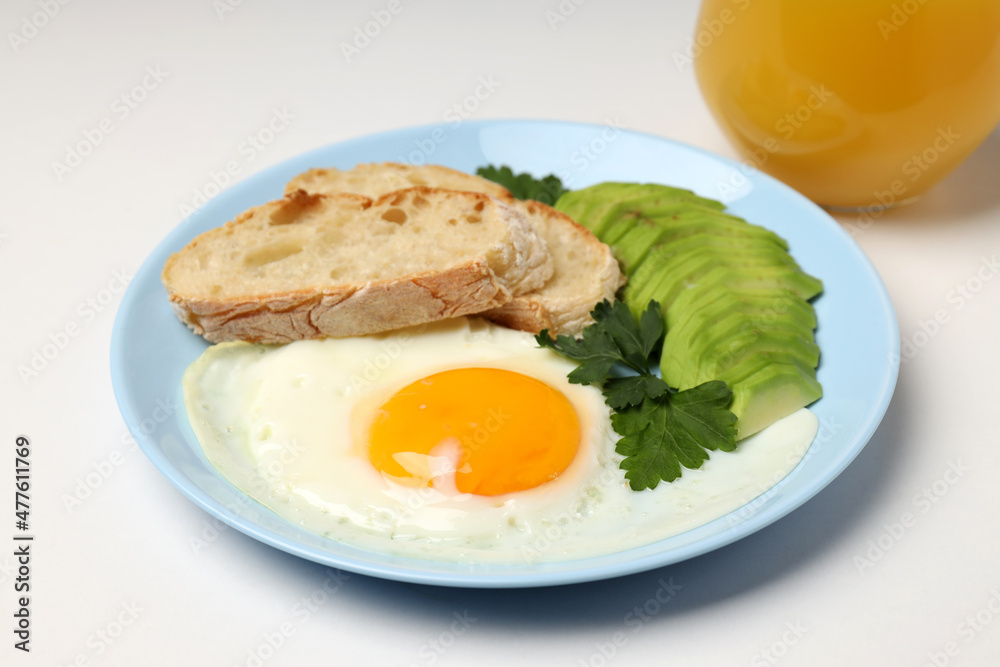Plate of breakfast and glass of juice on white background