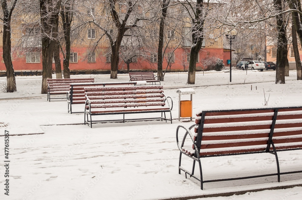Snow-covered benches and snowdrifts in a city park