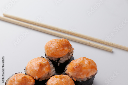 a portion of rolls on a stand, japanese food, sushi on the table, chinese chopsticks, light background