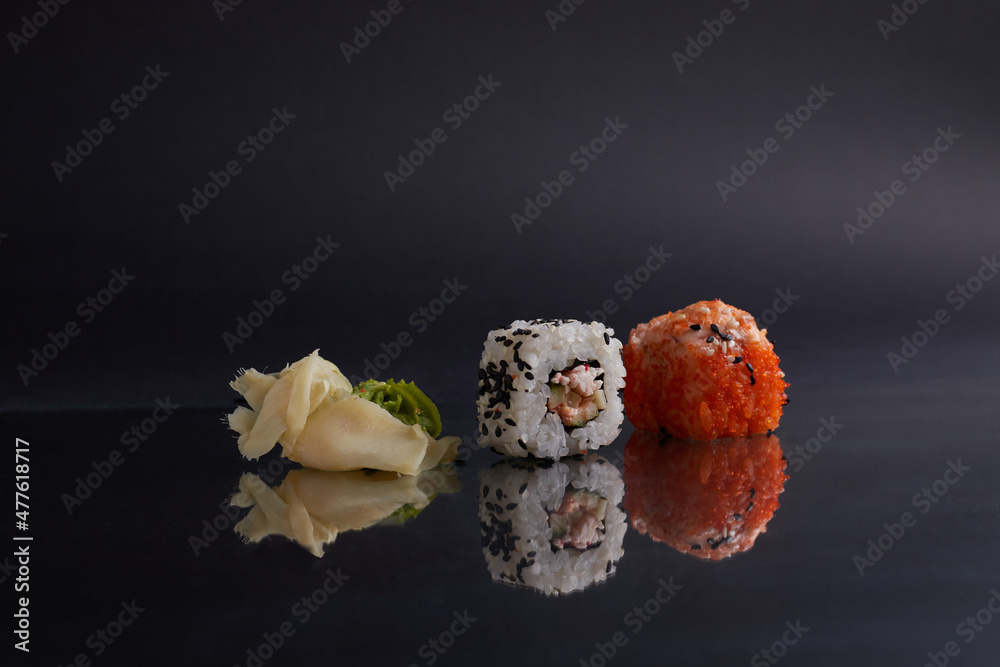 several different rolls on the table, asian food, side view, dark background, sushi, ginger and wasabi several different rolls on the table, asian food, side view, dark background, sushi, ginger and wasabi