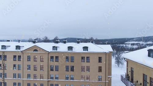 Apartment buildings during snowfall in Sweden, aerial ascend close up shot photo