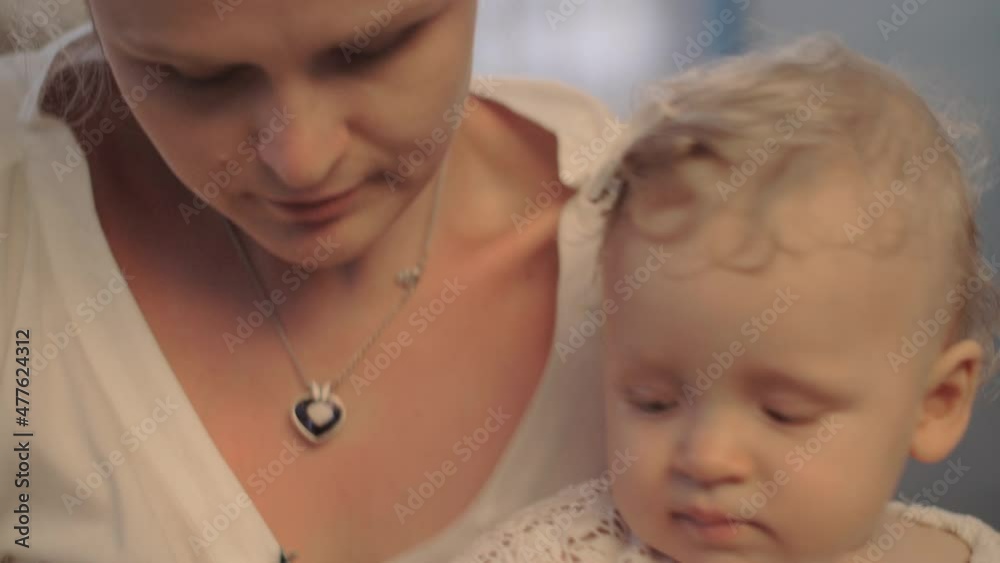 A woman holding a cute baby girl who is playing with a wooden pin A woman holding a cute baby girl who is playing with a wooden pin