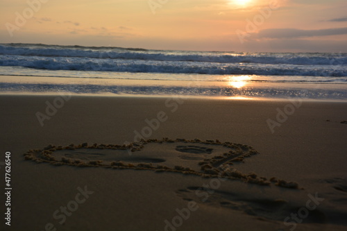 Heart of lovers painted in the sand by the sea at sunset in France