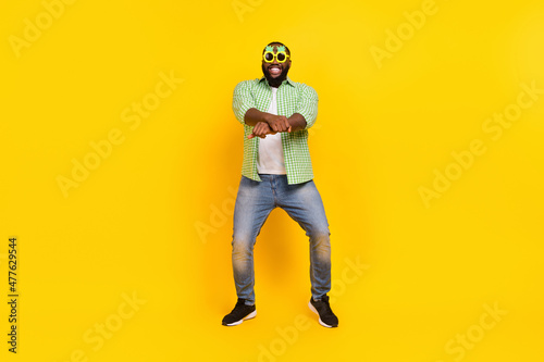 Full size photo of excited positive guy enjoy dancing crossed fists make moves toothy smile isolated on yellow color background