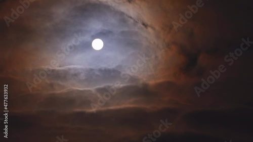 Full moon shining in the night sky as ghostly clouds blow past. These clouds are real and are illuminated by the moon itself. photo