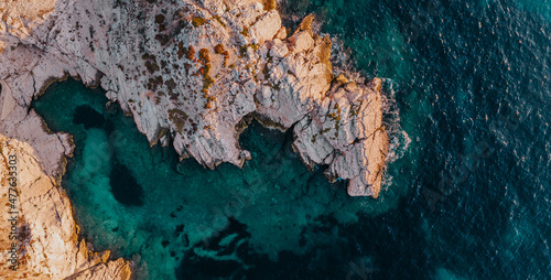 Photos Panoramic top down view of a rocky coast and deep blue crystalline waters during sunset