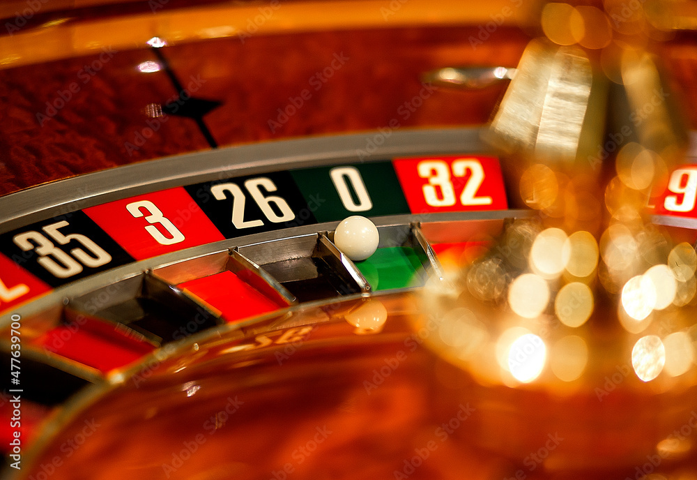 Roulette wheel in casino with ball on green position zero.
