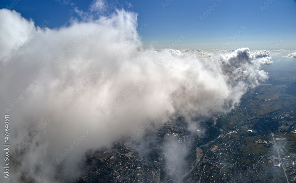 Aerial view from airplane window at high altitude of earth covered with puffy cumulus clouds forming before rainstorm