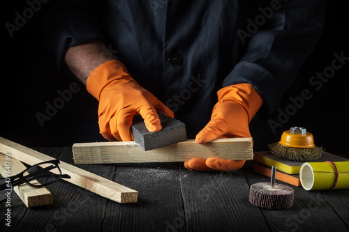 Fotografi Woodworker cleans a wooden plank with an abrasive tool