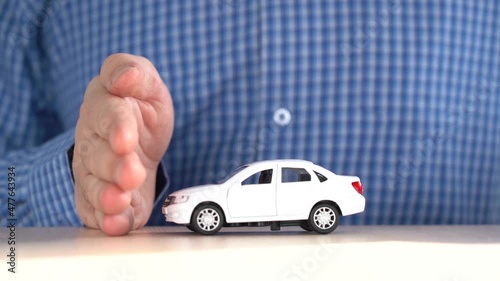 The toy car rides across the table to the palm. Auto insurance or auto safety concept photo