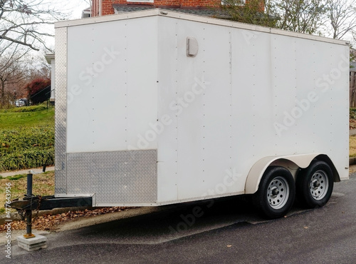 White  utility cargo trailer parked on residential city street.