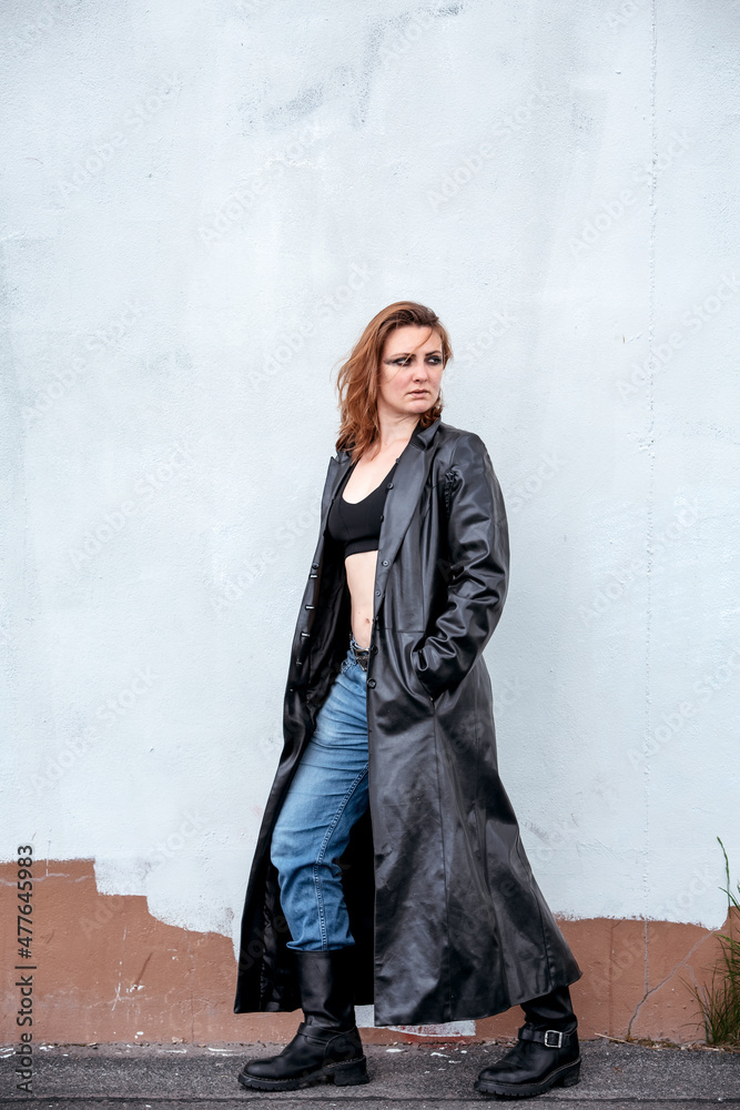 brunette woman in jeans and black leather coat standing on the street brunette woman in jeans and black leather coat standing on the street