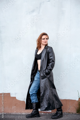 brunette woman in jeans and black leather coat standing on the street
