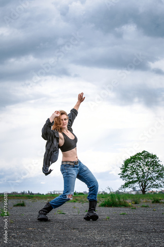 young woman in boots and jeans dancing at abandonded street