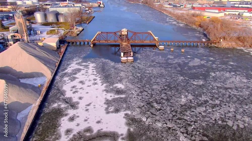 Low flyover, scenic view of old fashioned railroad train trestle bridge across icy river.
 photo