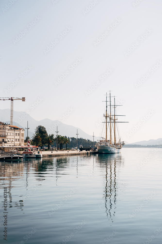 White sailboat and boats are moored at the pier of the town of Tivat