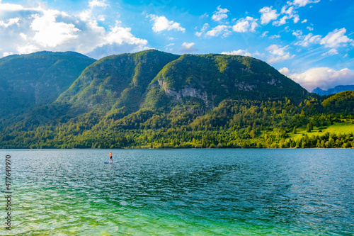 Moraine-dammed mountain lake Bohinji (Bohinjsko) in Slovenia, Europe with a tiny SUP boarder
