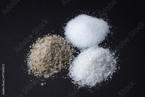 Different types of salt on a black background. Fine salt and salt with spices.