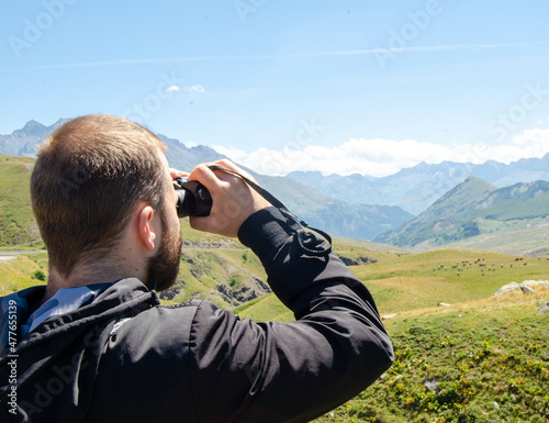 Man looking at the mountains with binoculars