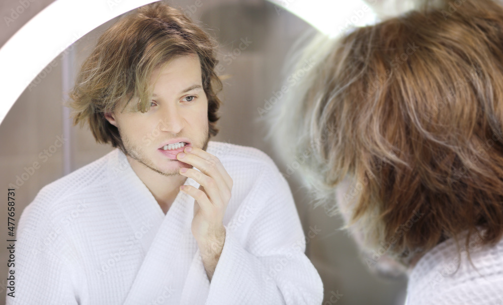 young man looking in the mirror,combing his hair,looking at problems on face. young man looking in the mirror,combing his hair,looking at problems on face.