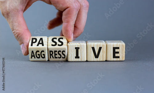 Passive or aggressive symbol. Businessman turns wooden cubes and changes the word passive to aggressive. Beautiful grey background, copy space. Business, psychological passive aggressive concept.