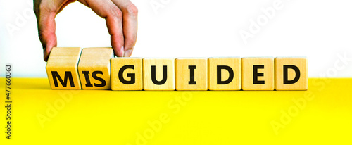 Guided or misguided symbol. Businessman turns wooden cubes and changes the word misguided to guided. Beautiful yellow table, white background, copy space. Business and guided or misguided concept.