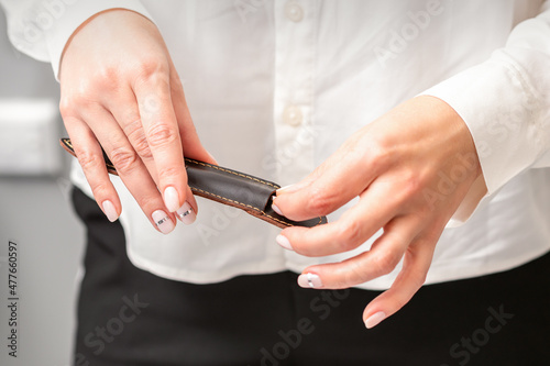Manicured hands and tools for a manicure. Hands of manicurist take off instrument for a manicure from the leather case in a nail salon
